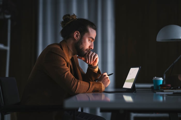 Person sitting at a desk looking at a laptop.