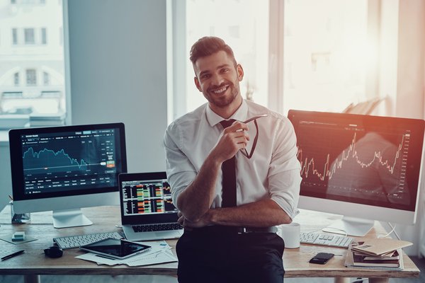 Person raises arms in success in front of computers.