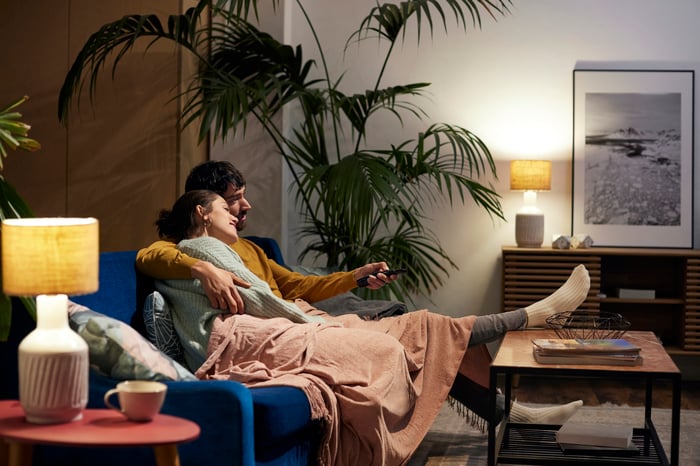 A young couple cuddling on the couch watching television.