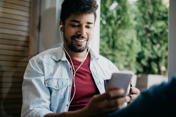 A person holding a coffee mug in their left hand while texting on their smartphone with their right hand. 