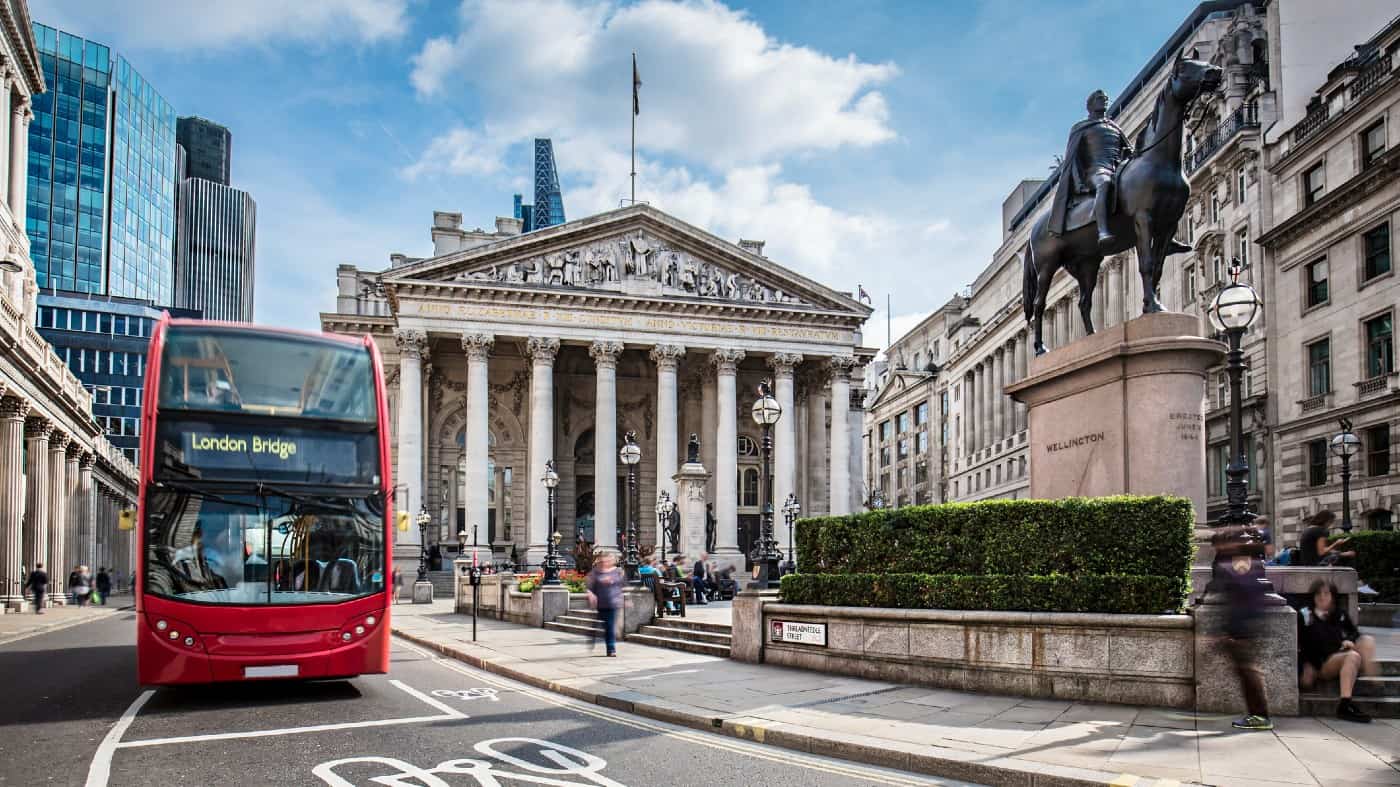 Bus waiting in front of the London Stock Exchange on a sunny day.