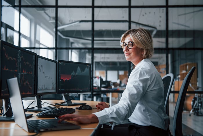 Smiling investor looking at stock charts on computer.