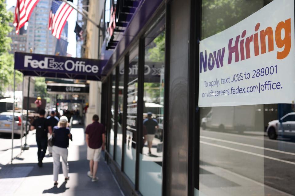 People walking and a Now Hiring sign at a FedEx Office location