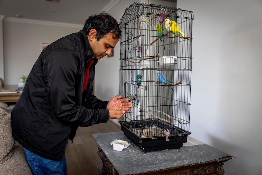 Karthik Sivasubramanian tends to a birdcage inside his home.