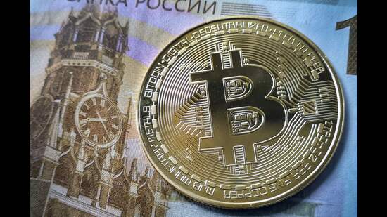 A souvenir bitcoin token is seen pictured with a 100 ruble bill in Moscow on July 30, 2024. Russian lawmakers voted on July 30, 2024 to tighten rules on petrocurrency mining, while also paving the way for it to be used in cross-border payments as a means to skirt Western sanctions. (Photo by Alexander NEMENOV / AFP) (AFP)