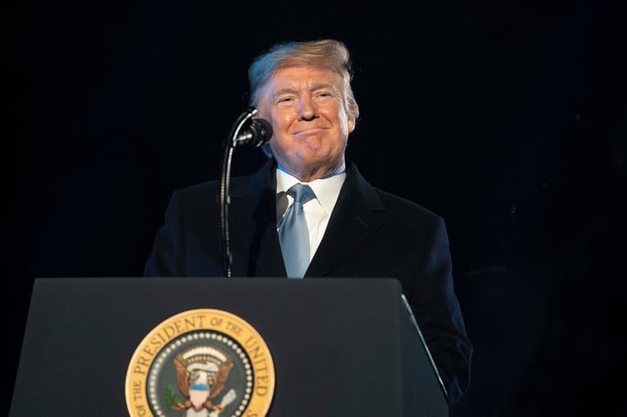 A smiling Donald Trump delivering remarks behind the presidential podium.