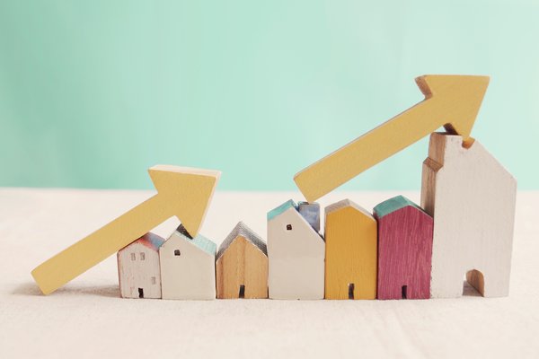 Toy houses stacked in a row with arrows pointing up at an incline.