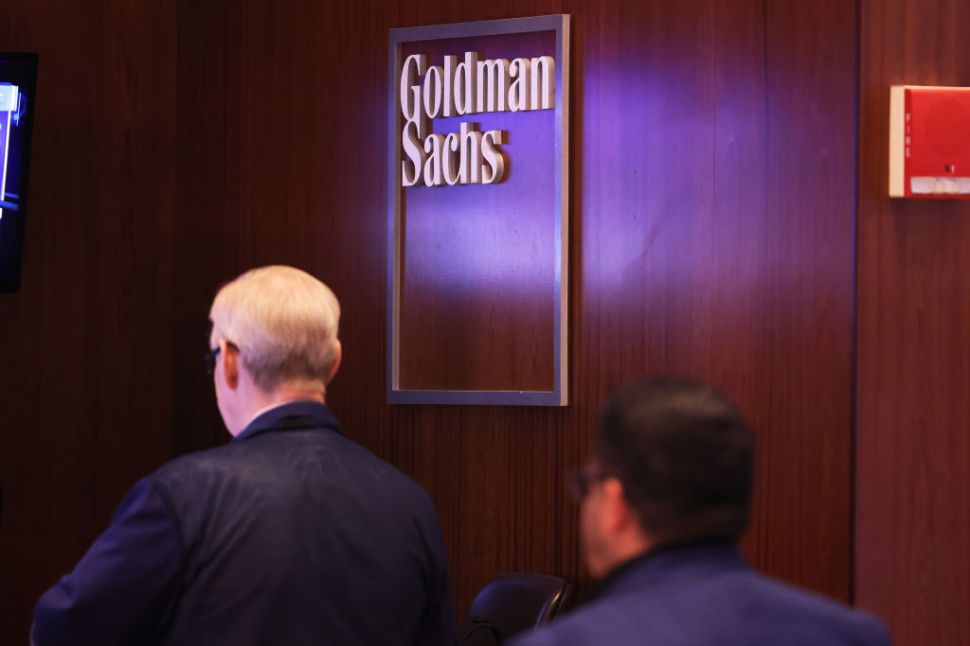 Two man in front of a Goldman Sachs logo