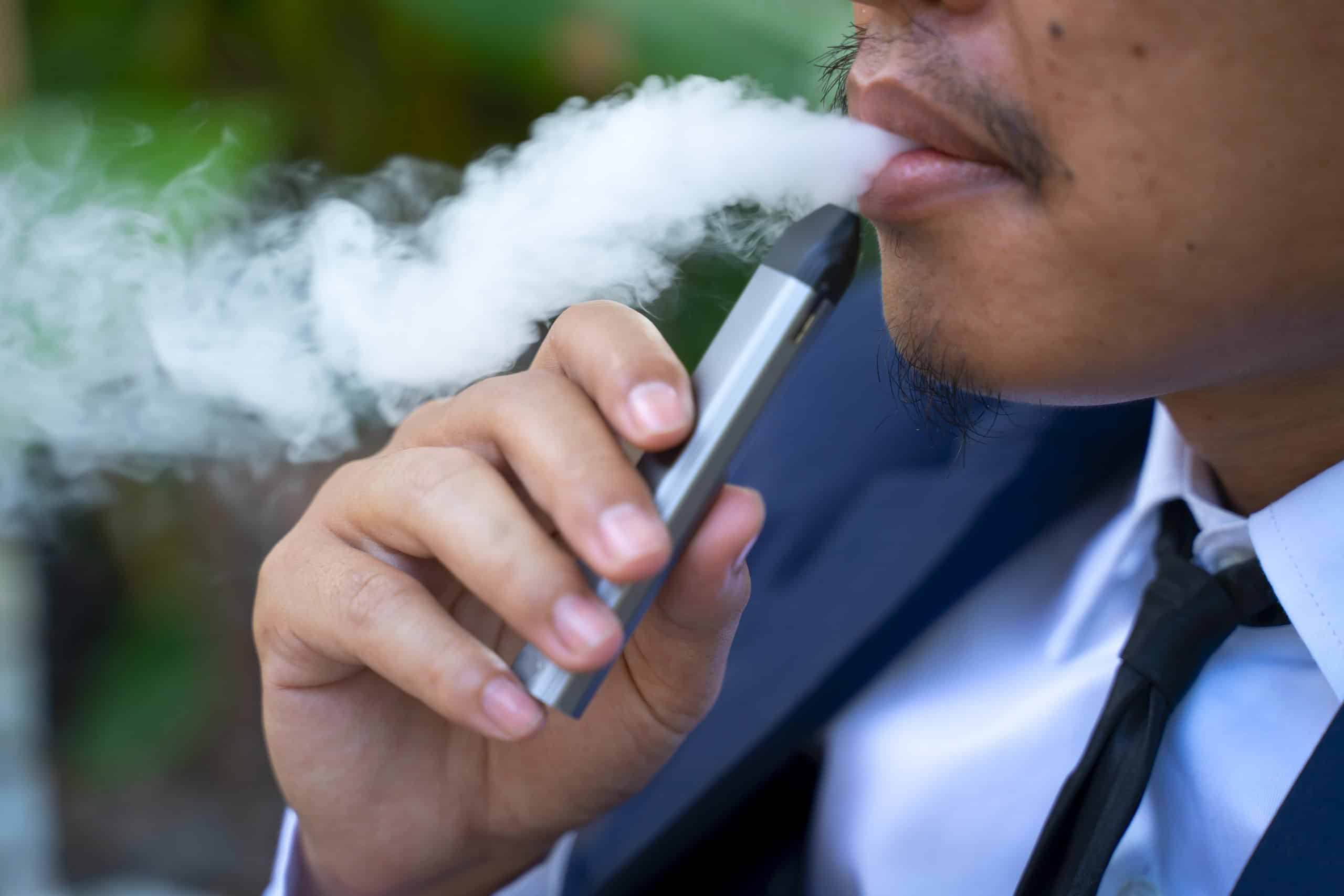 Young male worker smoking electronic cigarette