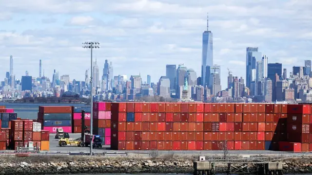 Shipping containers are seen at the Port Jersey Container Terminal, with the Manhattan skyline in the distance, in Jersey City