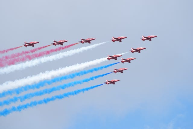 The Red Arrows form an arrow formation with plumes of red, white and blue smoke behind them