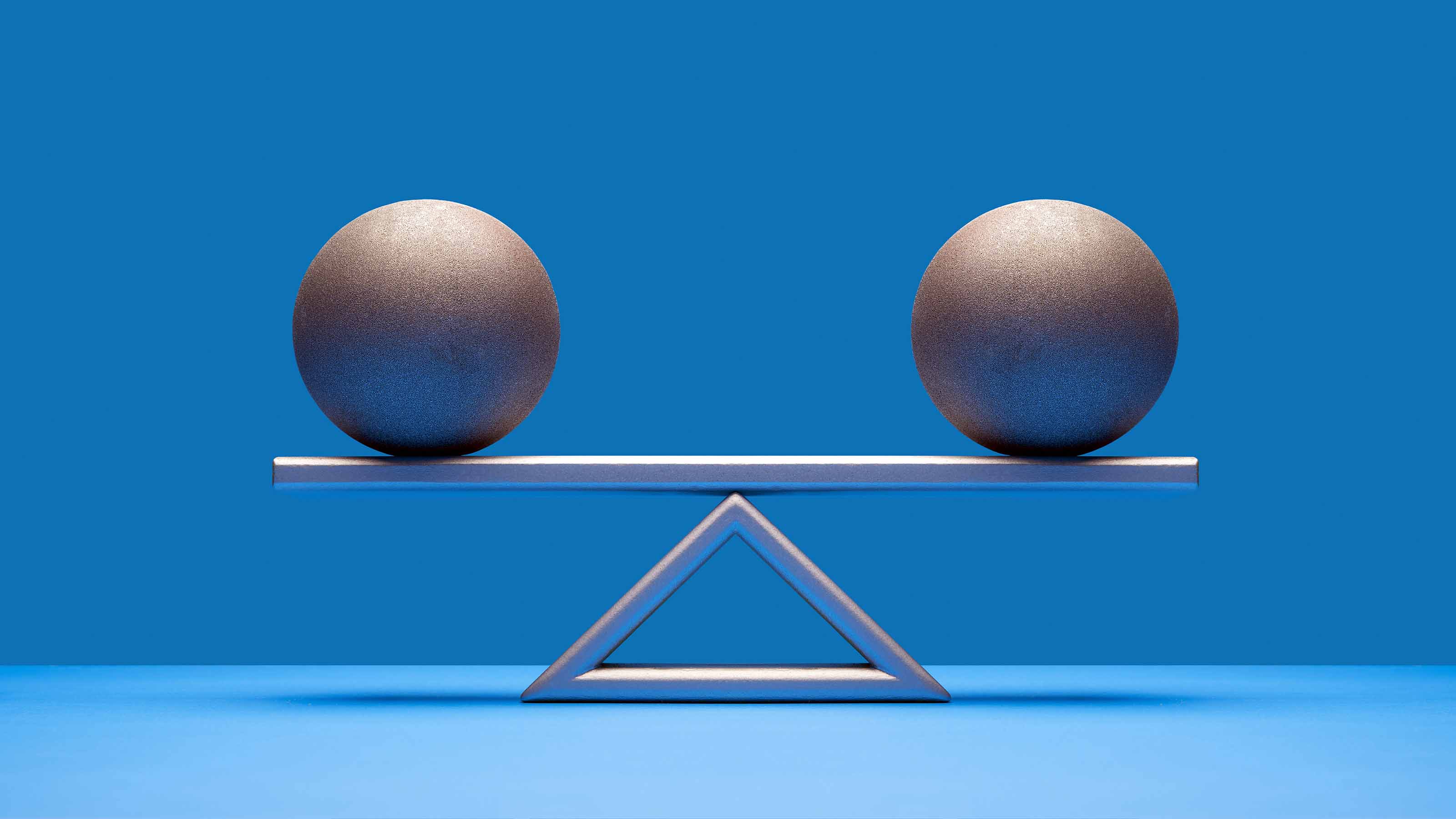 two silver balls equally balanced on scale