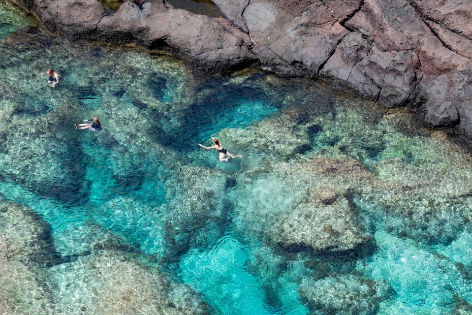 Tourists swimming in a natural ocean pool on Pitcairn Island.