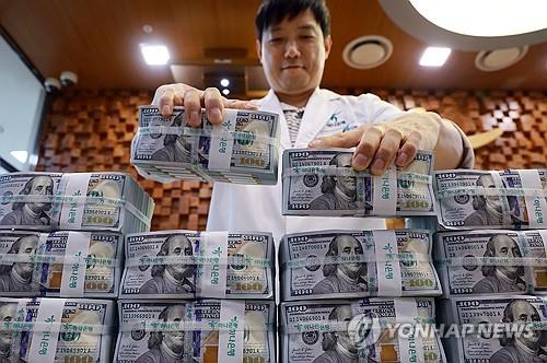 An official checks U.S. dollar notes at a bank branch of Hana Bank in central Seoul on July 7, 2025. (Yonhap)