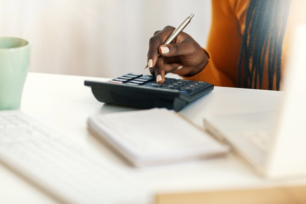 Hands of person typing on a calculator.