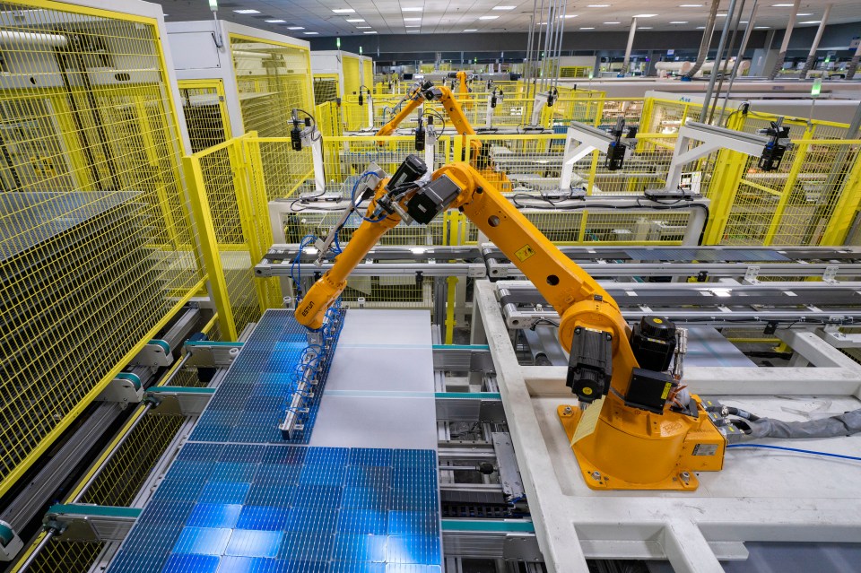 Robotic arms assembling solar panels on a factory production line.