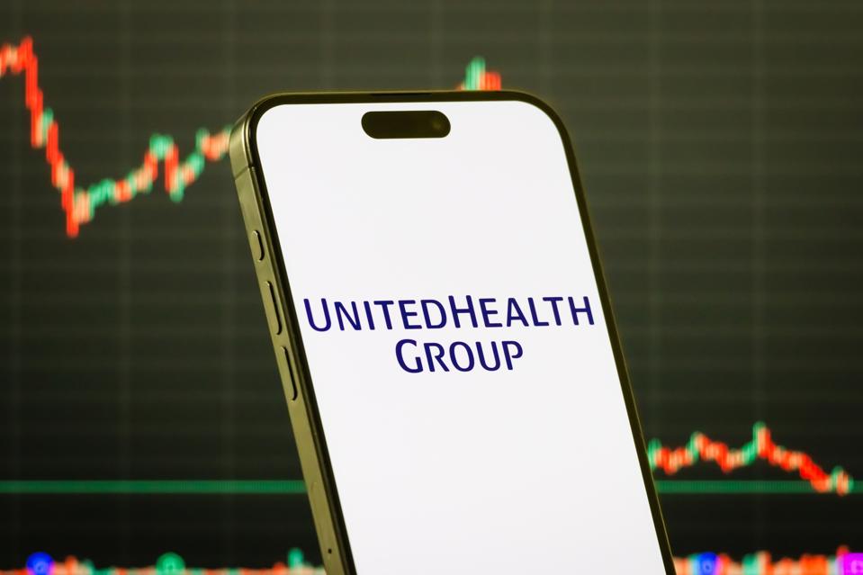 UnitedHealth Group logo on smartphone with stock market chart background