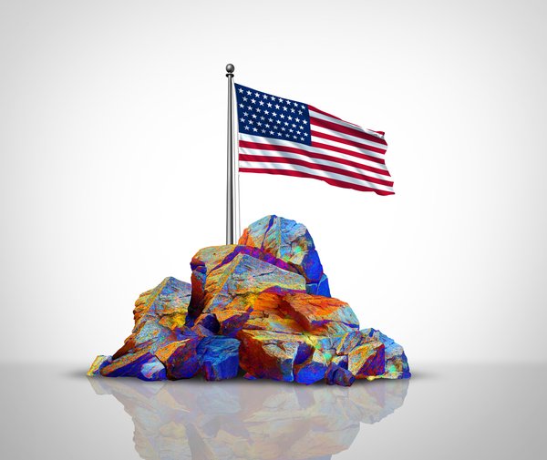 A pile of rare earth minerals with an American flag behind it.