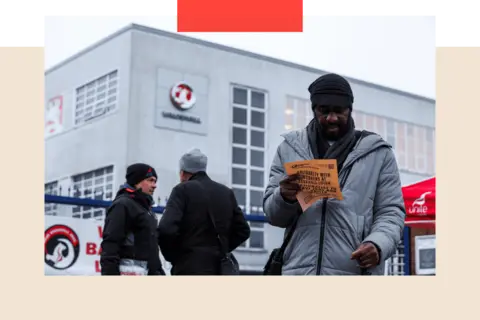 Reuters/ Chris Radburn A man holds a leaflet as workers protest following Stellantis' announcement of its plan to shut its Vauxhall van factory in Luton