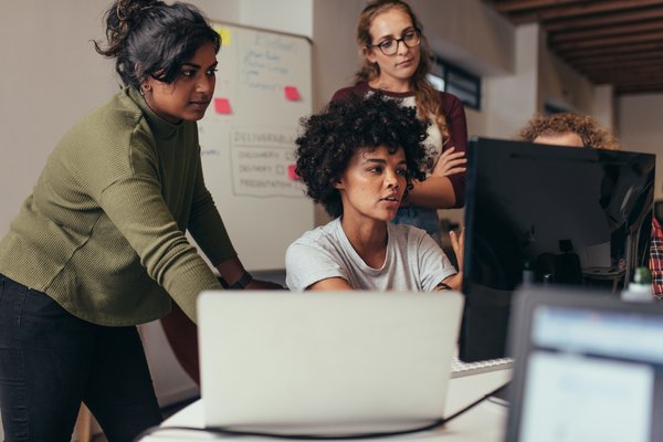 A group of people looking at a computer monitor.