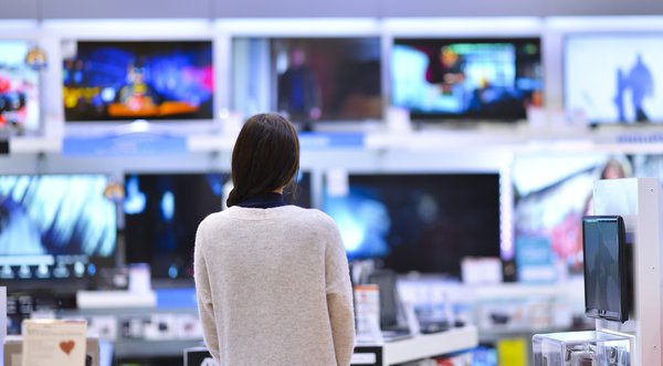 Person looking at many TVs while shopping in an electronics store.