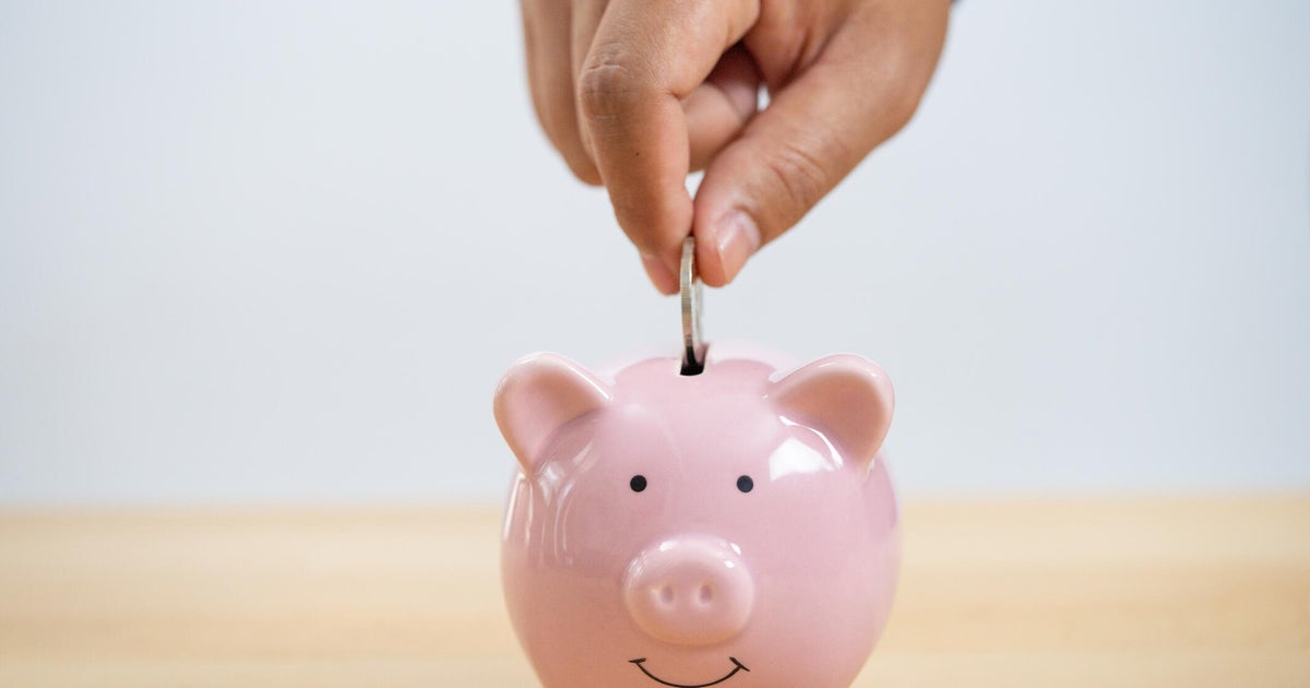 Businessperson's Hand Putting Coin In Piggybank 