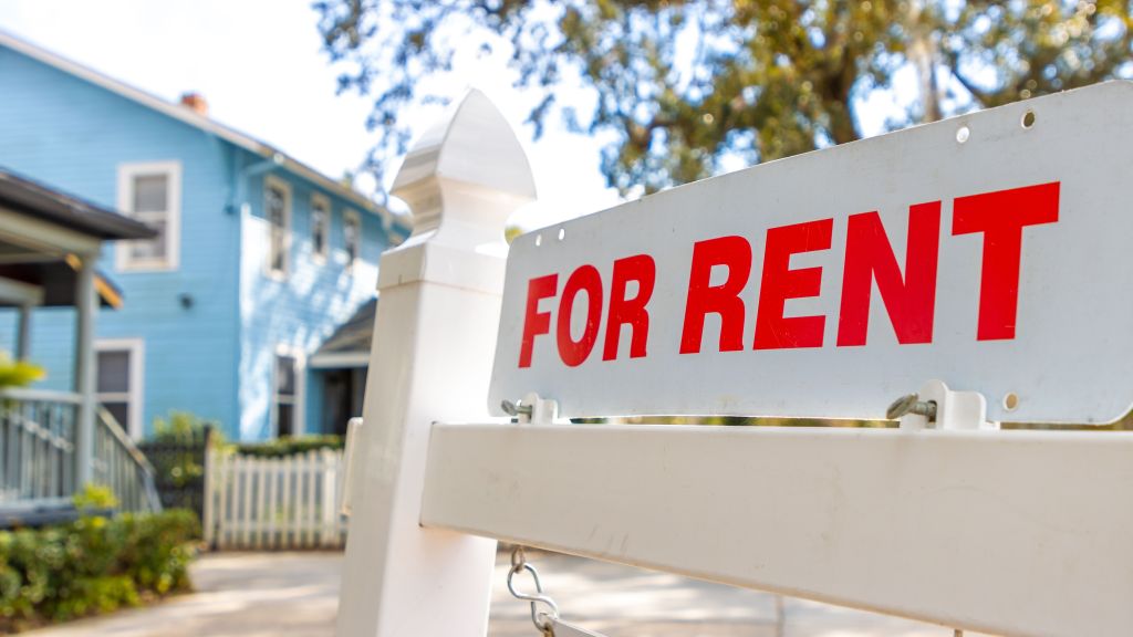 A for rent sign hangs in front of a single-family rental property. 
