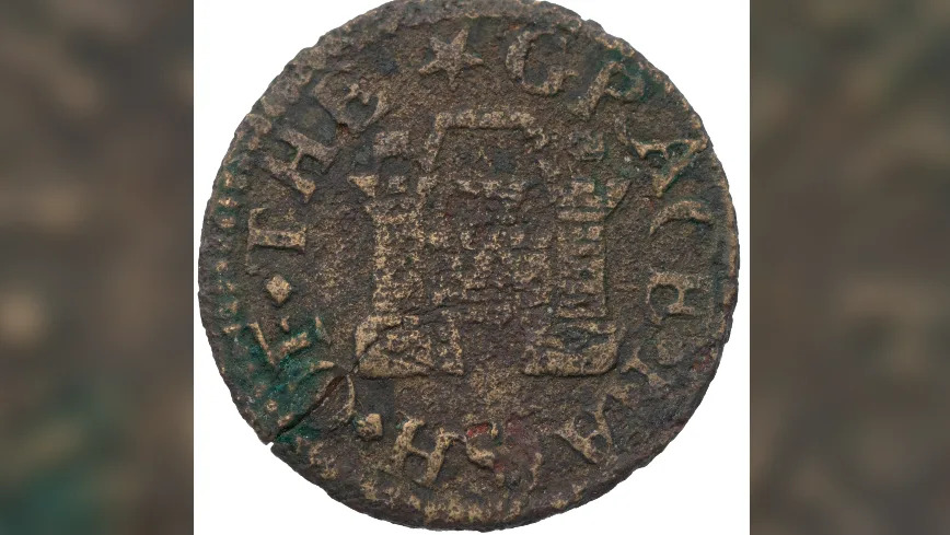 An old coin close-up: it is a very muddy copper colour and the imprint of a stylised castle can be seen in the middle with words round the edge - one of them says Grace in capitals