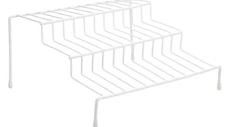 A white wire step shelf with three storage levels