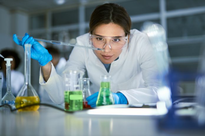 Female scientist examining liquid in laboratory.