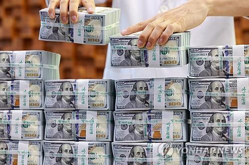 An official checks U.S. dollar notes at a bank branch of Hana Bank in central Seoul in this July 3, 2025, file photo. (Yonhap)