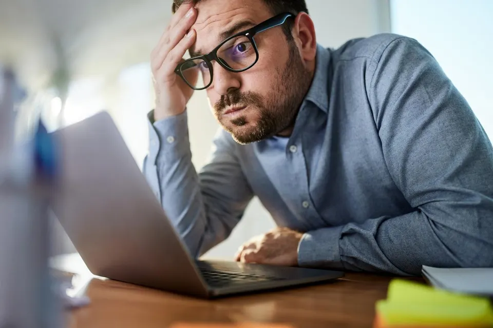 Worried businessman working on a computer at home office.