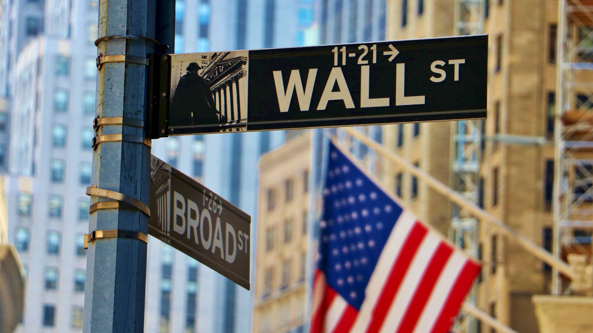 Photo shows American flag at the corner of Wall and Broad streets in New York