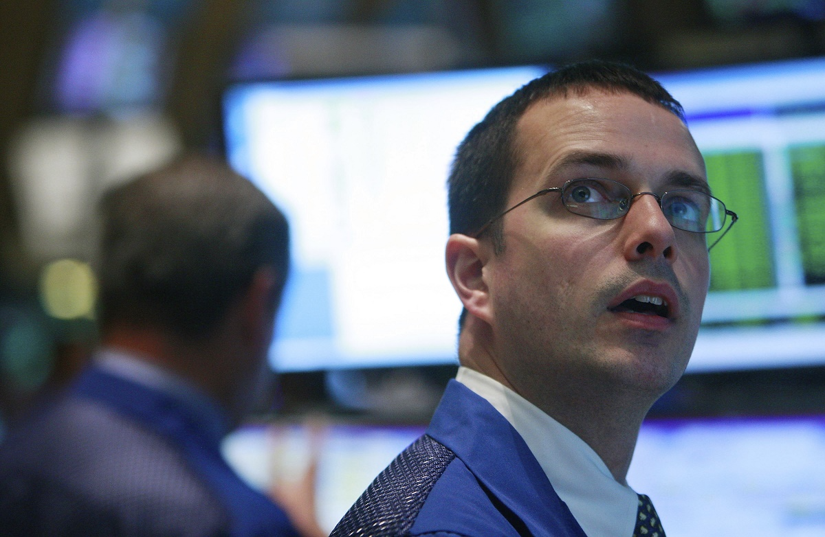 A trader looking up at stocks on a video screen. 