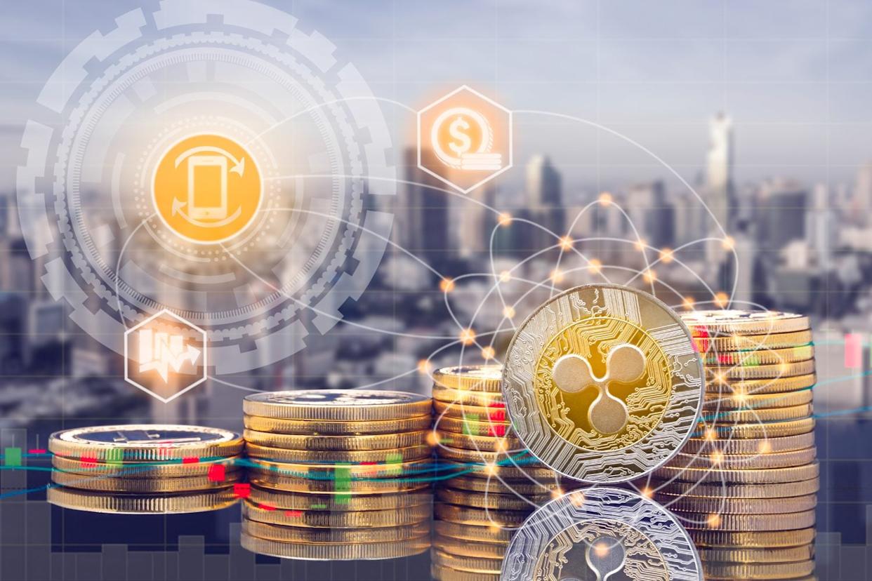 Ripple XRP and cryptocurrency investing concept - Physical Ripple coins with city background and exchange market trading price chart. Blockchain and financial technology.
