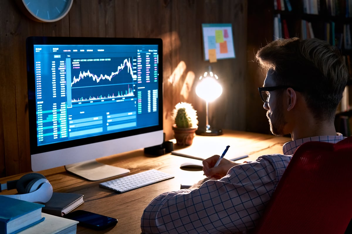 A person looking at screen with a chart while making calculations.