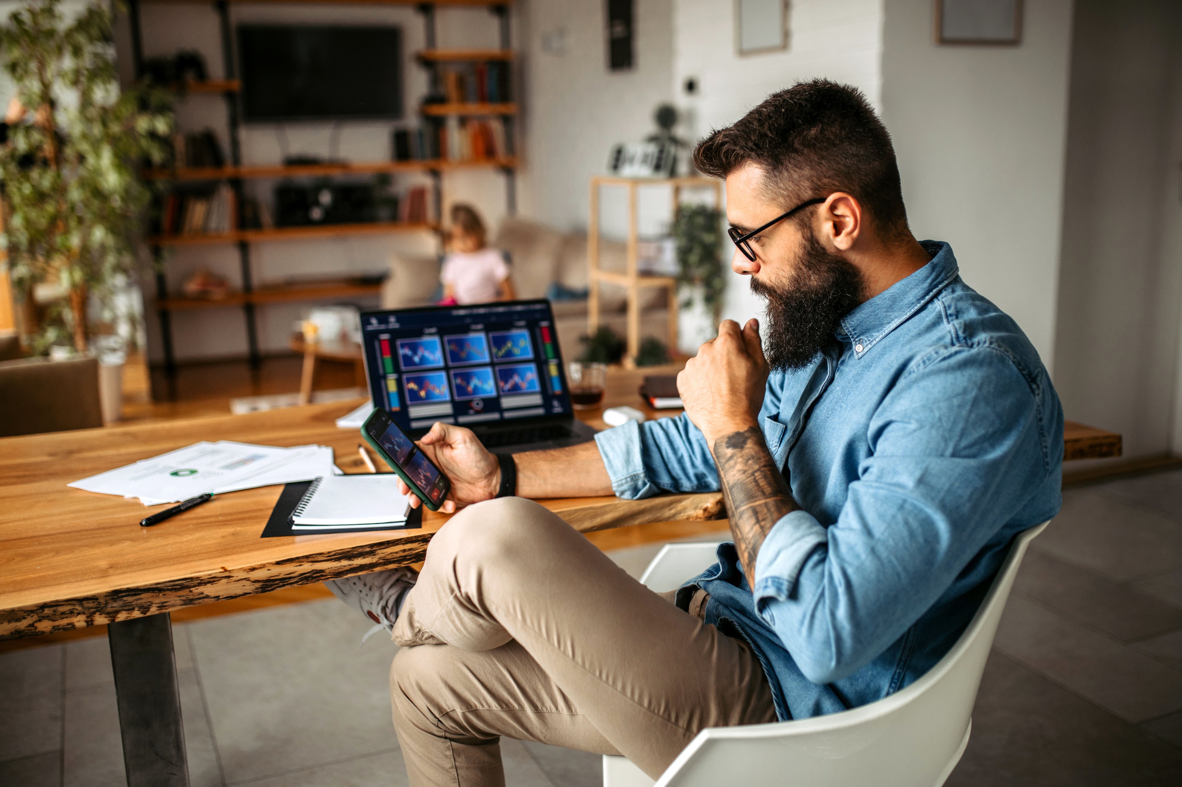 A person seated at a desk is using a smartphone.