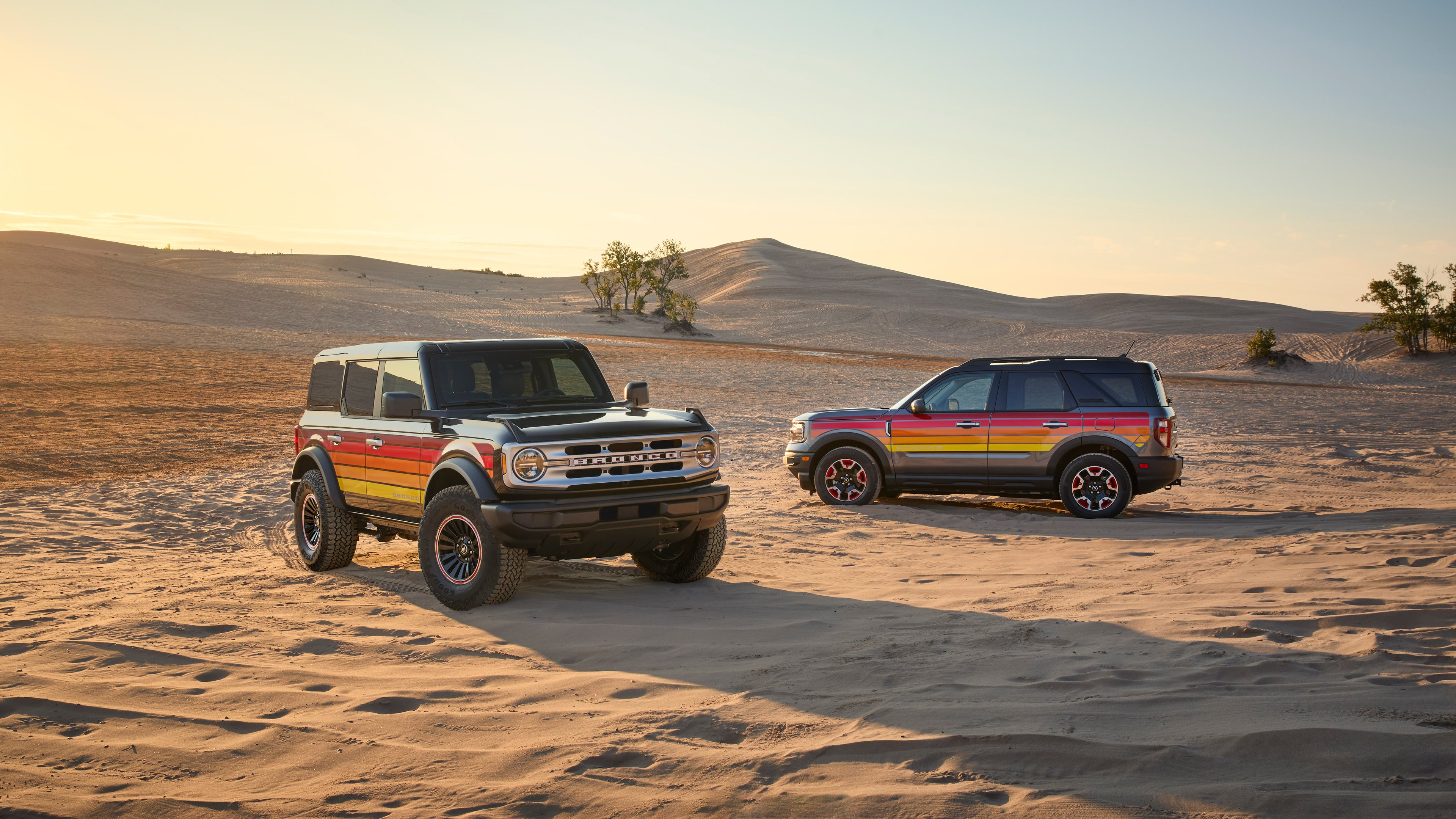 Two Ford Broncos parked on a beach.