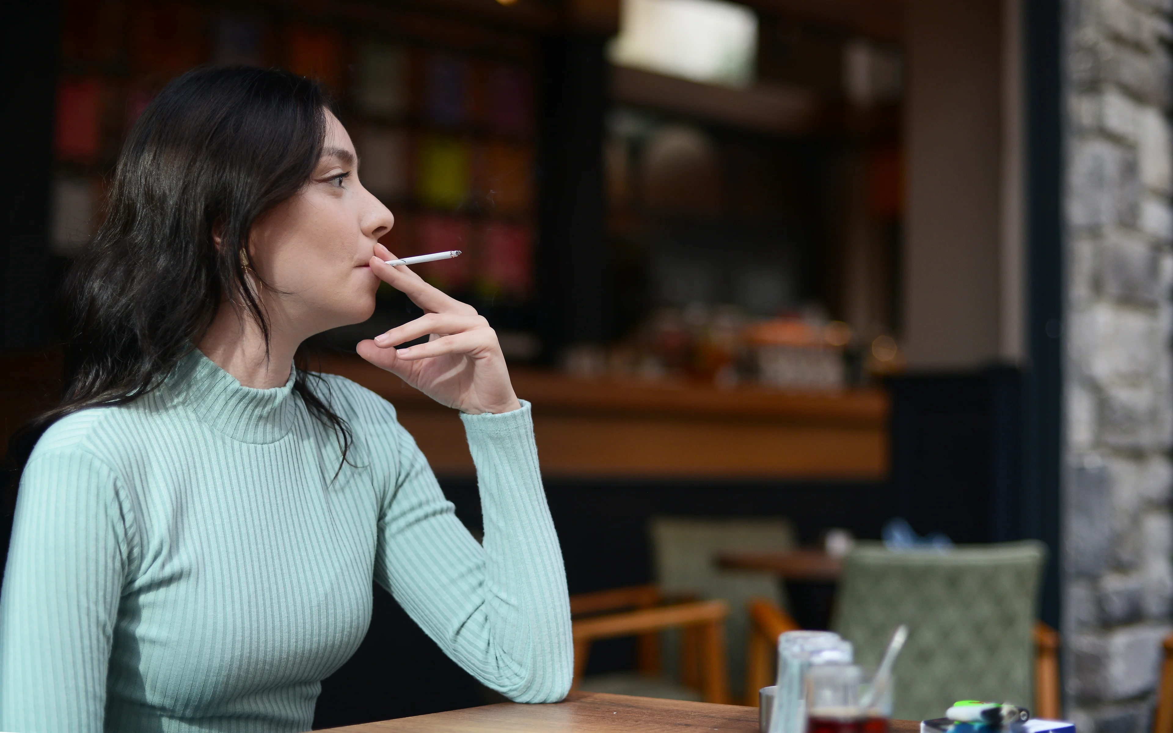 Person smoking while seated at a table.